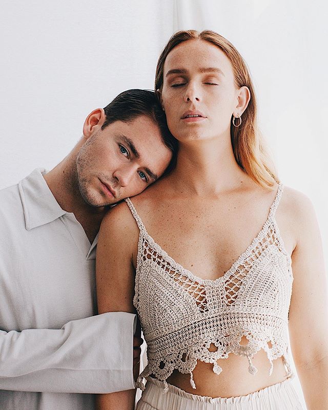 A man rests his head on a woman's shoulder in a tender embrace, showcasing minimalist style and natural lighting.