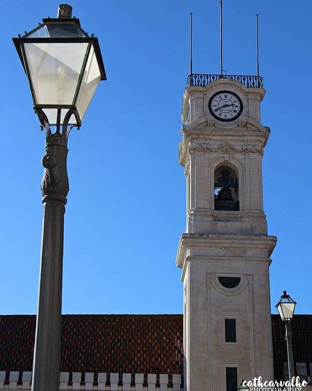 A clock tower and street lights against a clear blue sky provide a historical and serene urban scene.