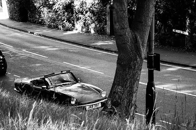 A vintage convertible car is parked near a tree, adding classic charm to the roadside scene.