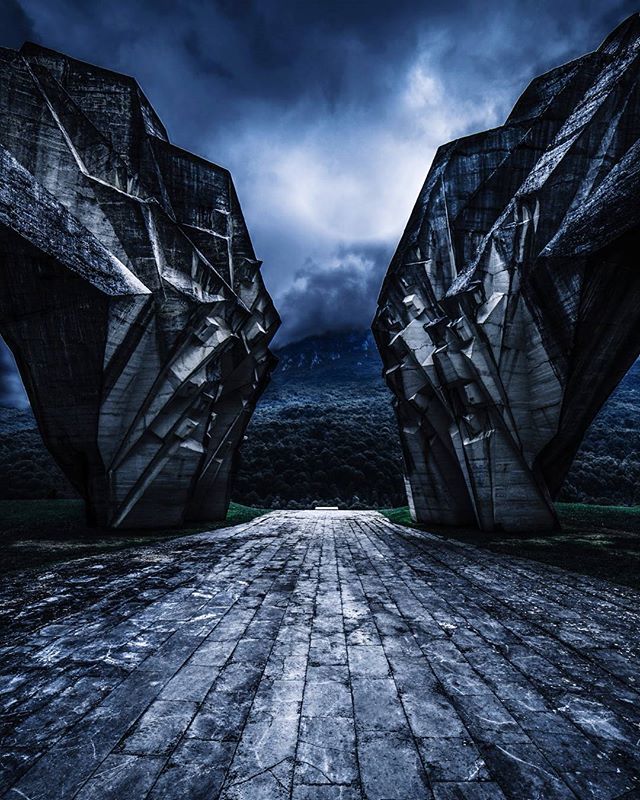 A dramatic, low-angle shot of a monumental concrete structure under a cloudy sky, evoking mystery and awe.