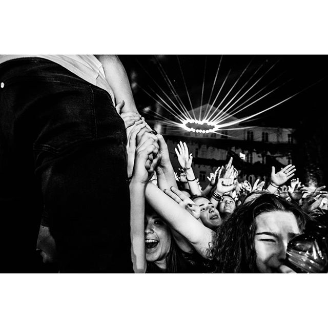 A crowd of fans reaches out at a music event, captured in black and white for a dynamic, street-style vibe.