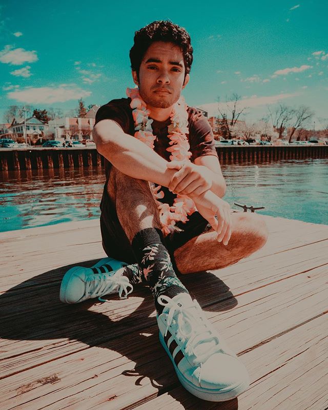 A man with a lei sits on a dock, creating a relaxed and serene atmosphere.
