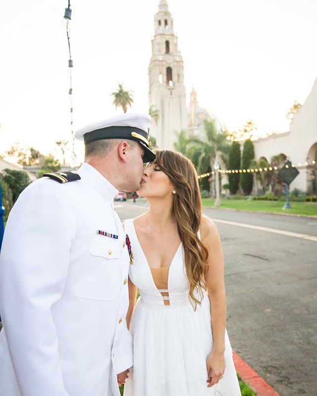 A bride and groom share a kiss on their wedding day in front of a beautiful building.