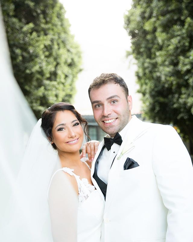 A happy bride and groom pose on their wedding day, celebrating love in a picturesque outdoor setting.