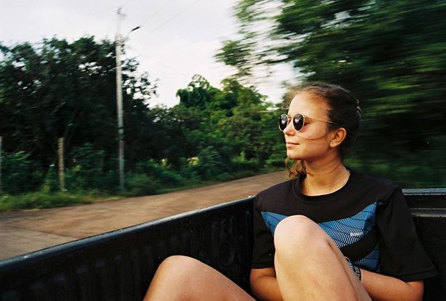A young woman enjoys a road trip, looking out at the passing scenery with her sunglasses on.