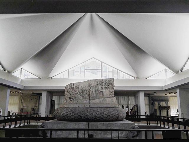 An interior shot featuring a sculpture in a museum with a modern architectural ceiling.