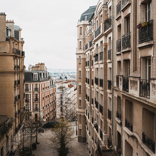 An urban scene features buildings lining a city street, capturing the essence of classic European architecture and serene city life.
