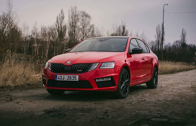 A red Skoda Octavia parked on a road under a cloudy sky, showcasing its modern design and urban appeal.