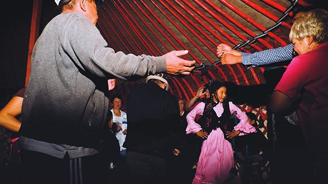 A group of people are dancing inside a yurt, celebrating a cultural event with lively energy and joy.