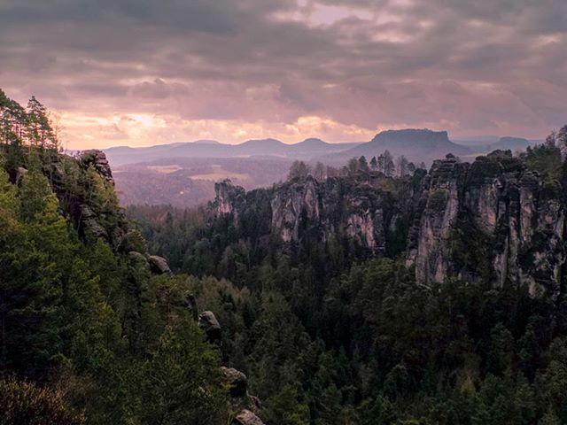 A scenic view of a forest and mountain range under a cloudy sky, perfect for nature tourism and environmental themes.