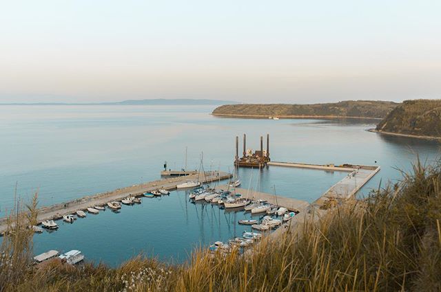 A serene harbor scene with boats docked along the coastline, capturing a calm coastal atmosphere.