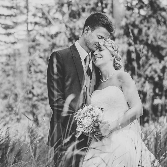 A happy bride and groom embrace in a field on their wedding day.