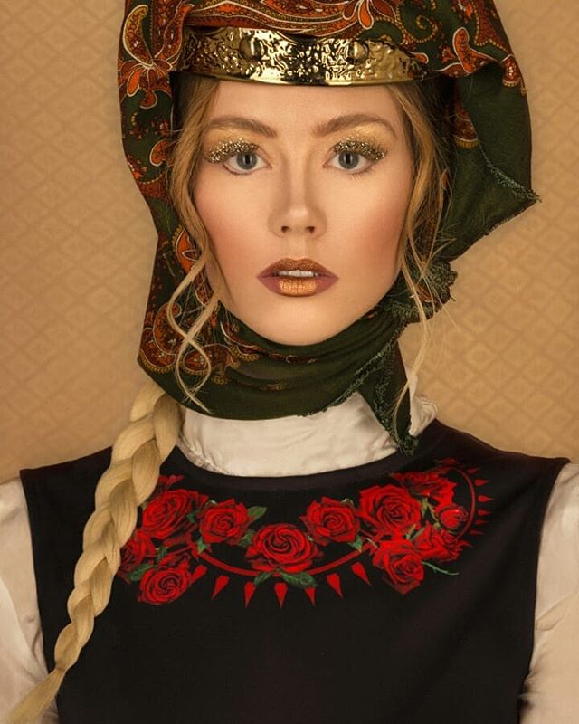A woman with gold makeup and a headscarf poses in a vintage-style portrait.