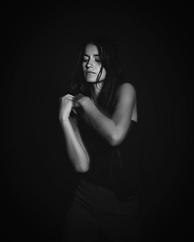 A woman with closed eyes poses in a thoughtful and emotional black and white portrait.