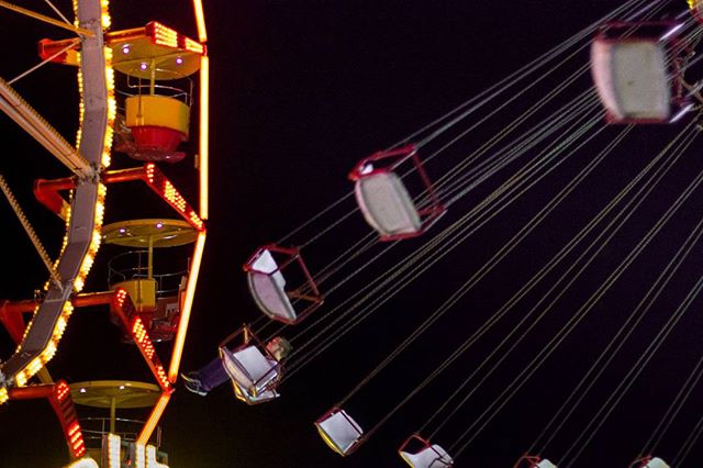 A vibrant shot of carnival rides at night, with blurred motion and bright lights creating a sense of excitement.