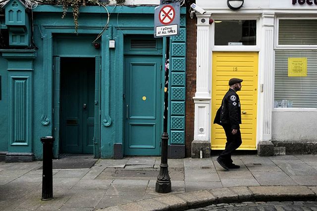 A man walks by colorful buildings on a city street, capturing an everyday urban scene.