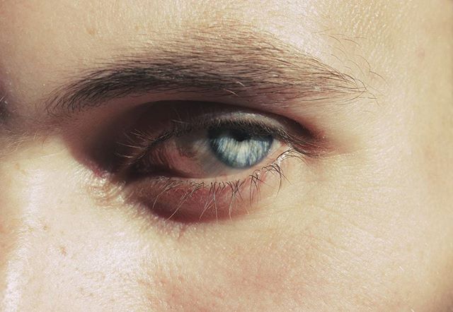 A close-up shot features a piercing blue human eye, capturing its intricate details in sharp focus.