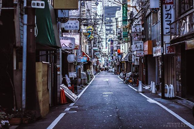 A narrow Tokyo street is framed by dense signs and overhead cables, offering a glimpse into the city's unique urban landscape.