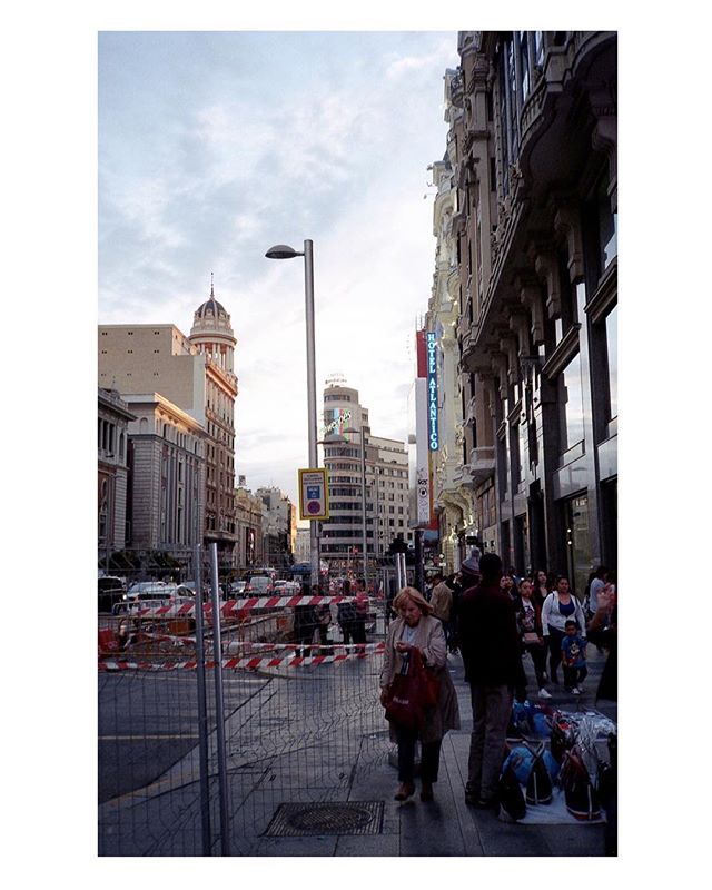A bustling city street in Madrid, Spain, shows people walking by construction.