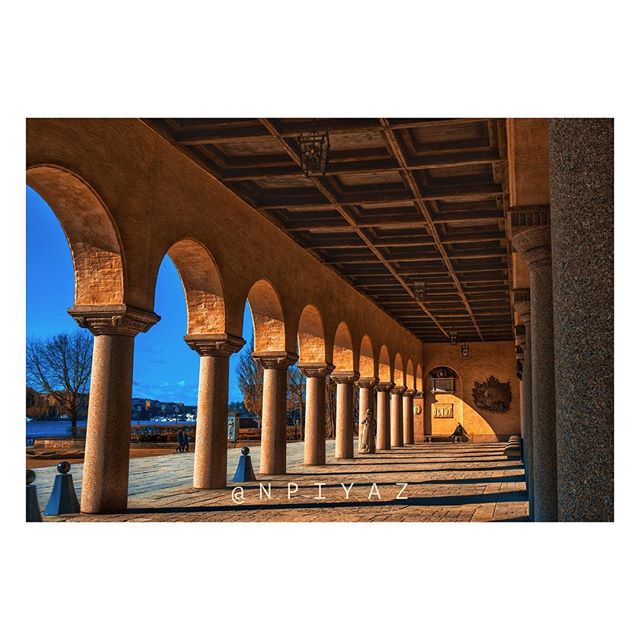 An arched colonnade with stone pillars on a sunny day captures historical architecture and serene urban scenery.