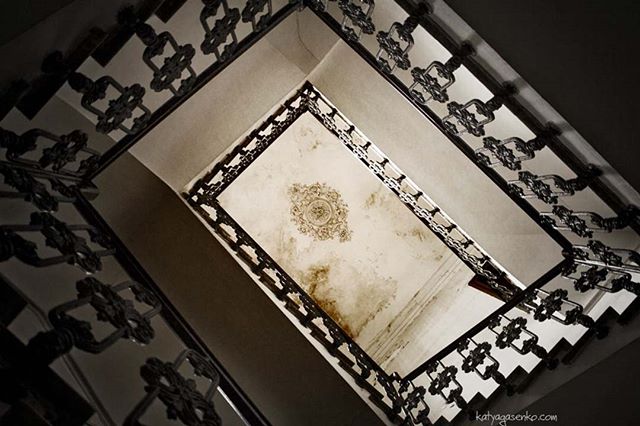 A worm's-eye view showcases the intricate details of a vintage staircase and ornate ceiling.