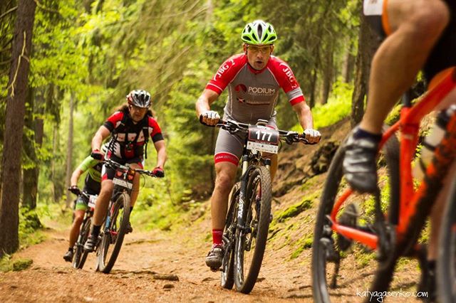 A group of cyclists compete in a mountain biking race on a forest trail.