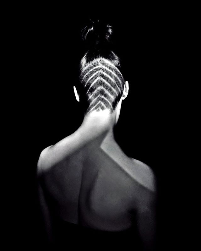Back view of a woman with an artistic haircut, captured in high-contrast black and white.