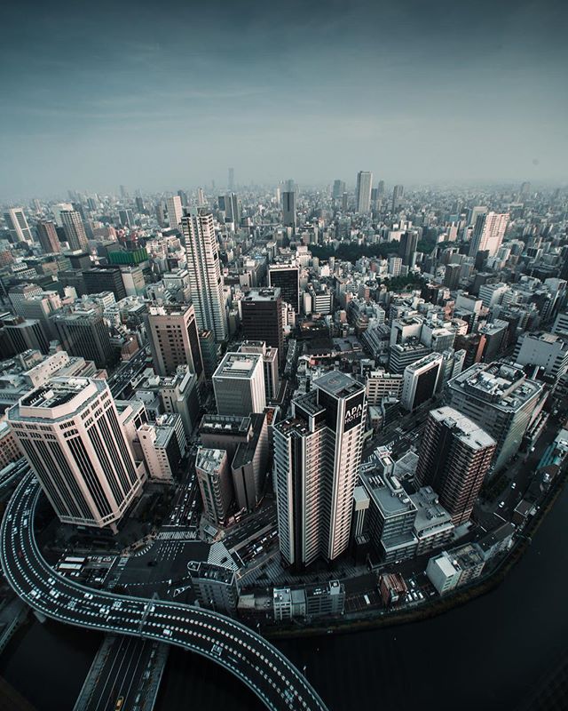 An aerial view of a modern city with skyscrapers and roads under a cloudy sky, perfect for travel and urban development themes.