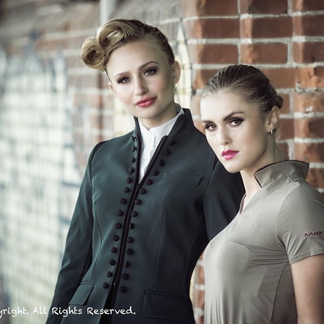 Two elegant women pose in front of a brick wall, showcasing sophisticated and modern fashion.