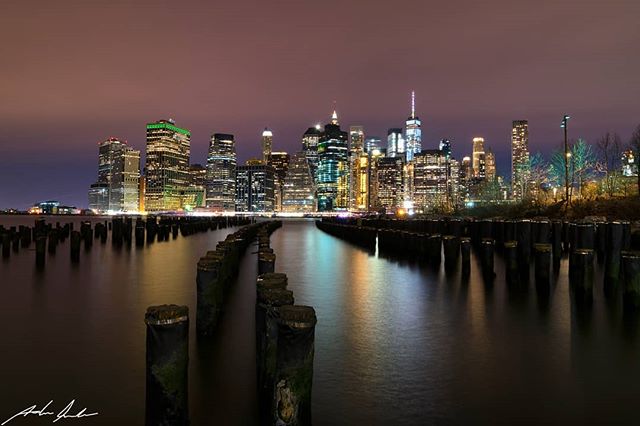 Night view of the New York City skyline over water with docks. Peaceful cityscape for travel, urban lifestyle.