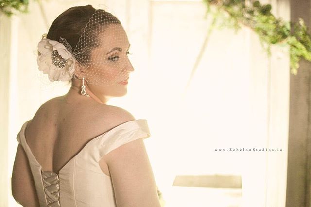 A bride with a veiled headpiece looks over her shoulder, in a soft, dreamy wedding portrait.