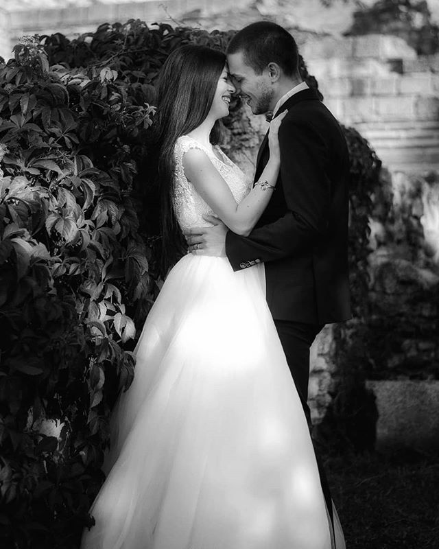 A bride and groom embrace in a black and white wedding photo filled with love and tenderness.