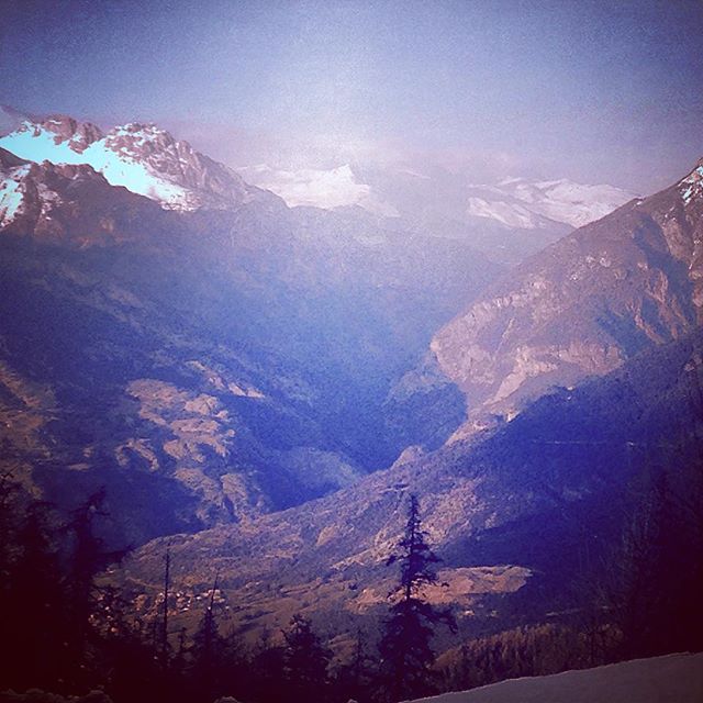 A scenic mountain range featuring snow-capped peaks and a lush valley, creating a tranquil landscape.