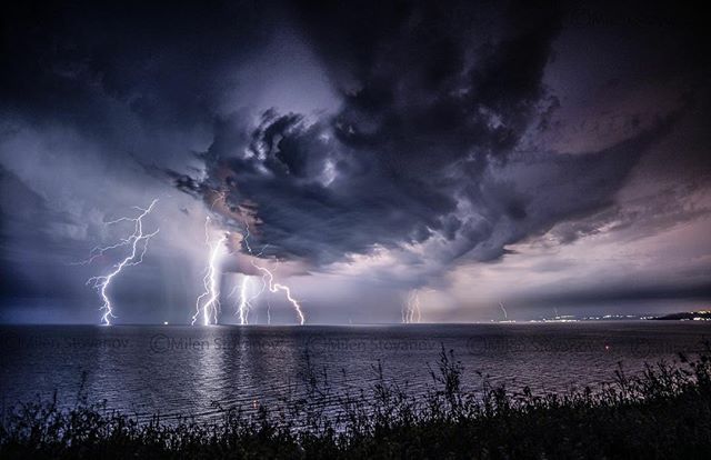 Lightning strikes over the sea during a powerful storm, showcasing dramatic weather.