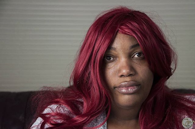 Portrait of a woman with red hair looking directly at the camera, indoors.