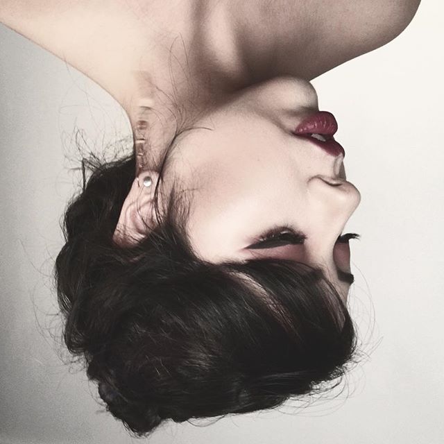 Close-up editorial style shot of a woman with dramatic eye makeup and red lipstick in a studio setting.