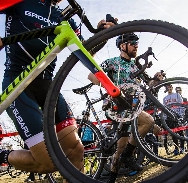Cyclists carry their bicycles during a cyclocross race, showcasing determination and athleticism in a dynamic outdoor setting.