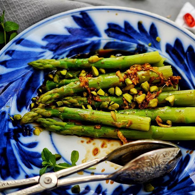 A plate of asparagus topped with pistachios, a fresh and flavorful dish. Great for healthy eating.