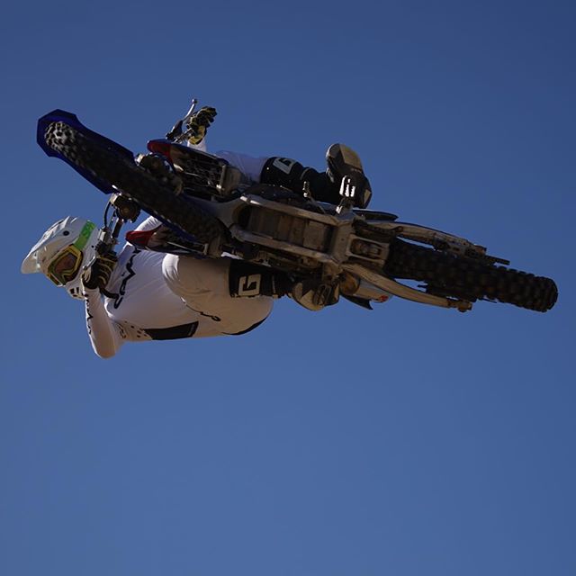 A motocross rider performs a trick in the air against a clear blue sky.