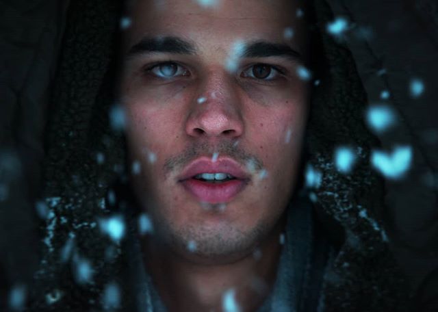 Intense close-up of a man's face with snowflakes, capturing a strong, emotional mood in a snowy winter setting.