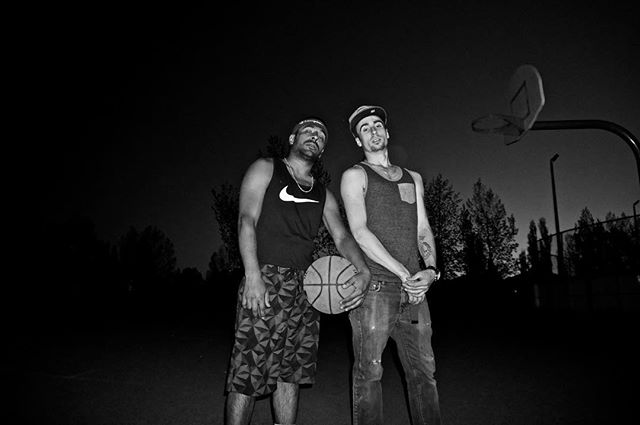 Two men pose with a basketball on an urban court at night, showcasing an active and confident lifestyle.