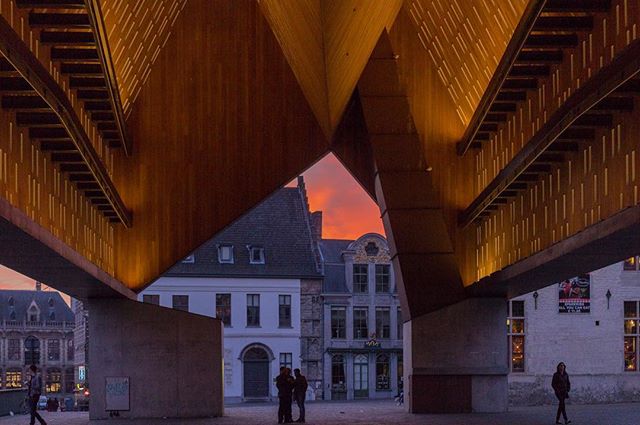 A modern architectural structure frames a street view at sunset, showcasing urban design and atmosphere.