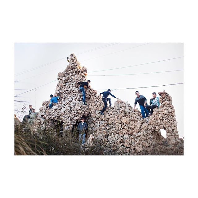 A group of young men climb a unique rock formation, enjoying an outdoor adventure on a hillside.
