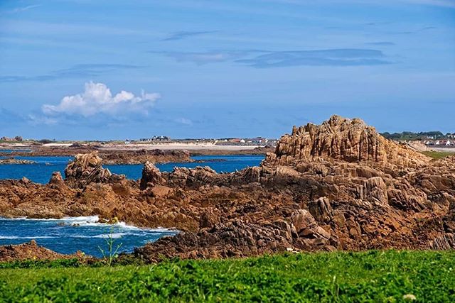 Scenic view of a rocky coastline with the ocean under a blue sky, perfect for travel and tourism marketing.