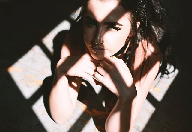 A brunette woman poses in soft lighting, a sensual close-up ideal for editorial or advertising.