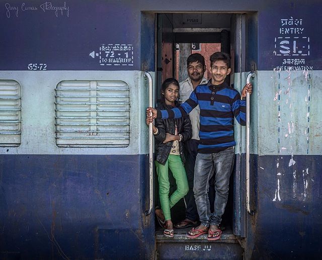 A family stands in the doorway of a blue train car, ready for adventure and travel. 