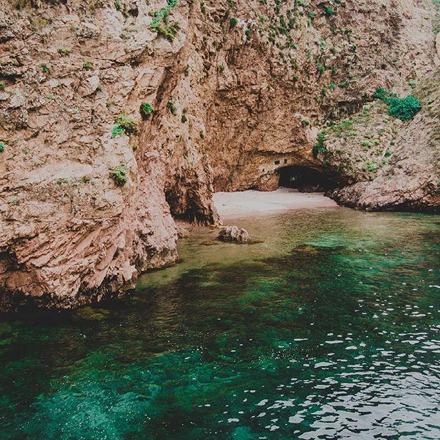 A secluded beach cove featuring clear turquoise waters and rugged rock formations. Peaceful coastal scenery.