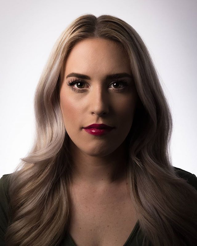 A portrait of a woman with blonde hair and red lipstick in a studio setting.