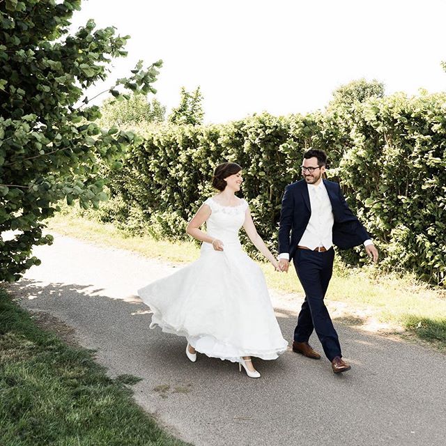 A bride and groom happily stroll down a path on their wedding day.