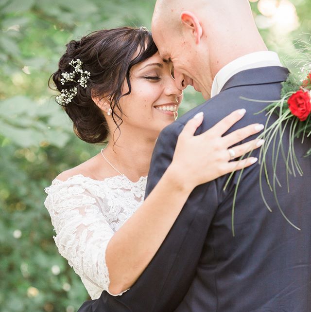 A smiling bride embraces her groom in a loving moment during their outdoor wedding ceremony.